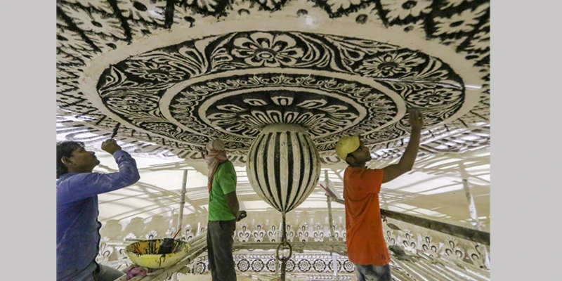 Craftsmen repair and paint the ceiling medallion at the Tomb of Abdullah Qutb Shah